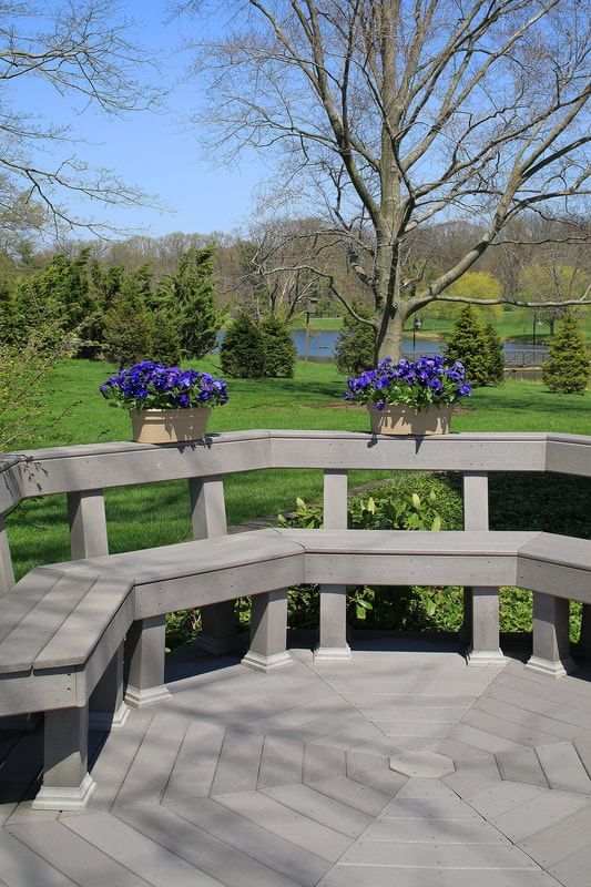 Gray curved bench with purple flower planters overlooking green lawn and trees at Aramark Chauncey Conference Center