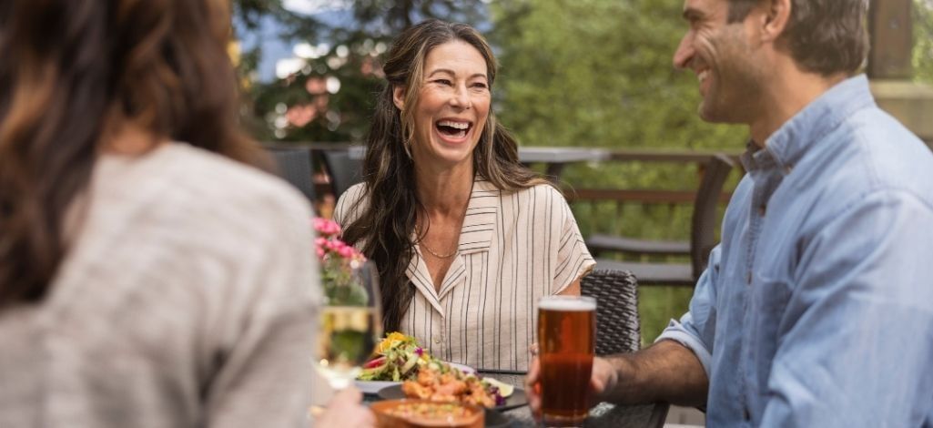 Guests dining together on an outdoor patio at The Raven Room in Whistler