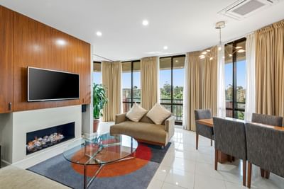 Living area with TV and dining table in the Three Bedroom Riverview Penthouse at Amora Herencia Riverwalk Melbourne