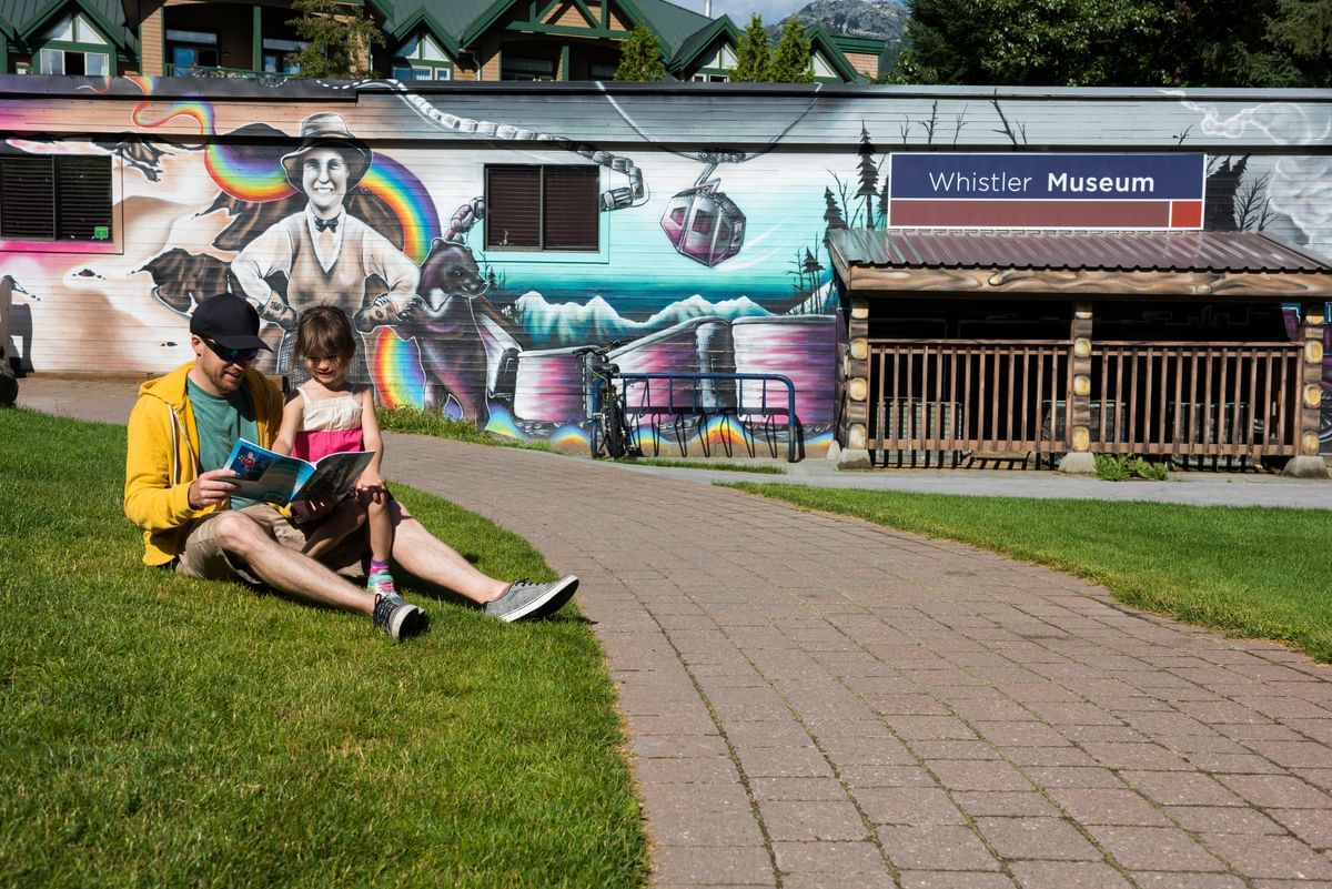 Man with a girl sitting by the Whistler Museum near Blackcomb Springs Suites