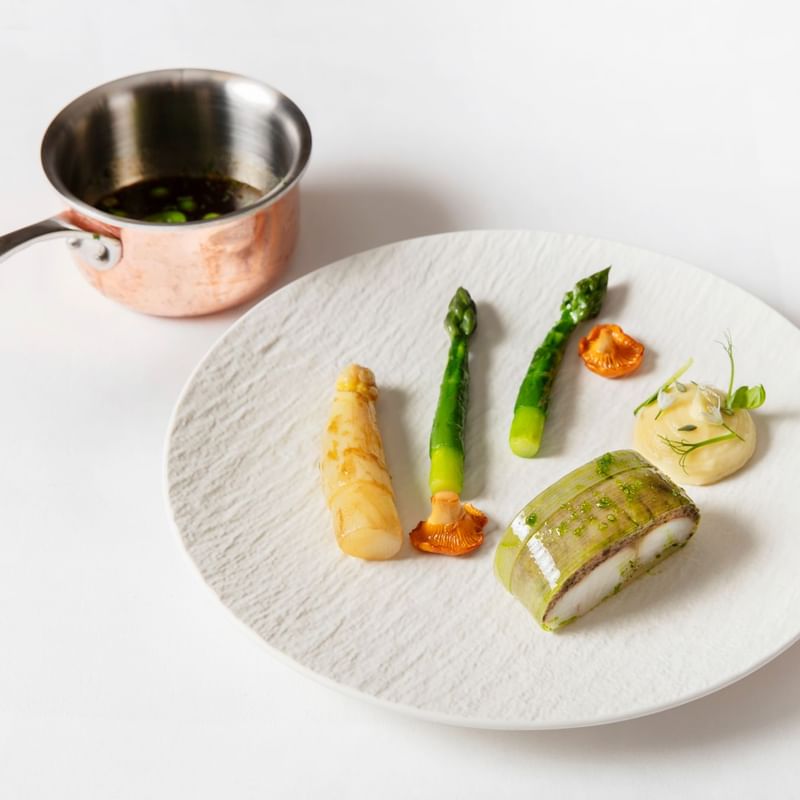 Dining dish featuring fresh asparagus, mushrooms, and a delicate fish fillet at Warwick Hotels and Resorts