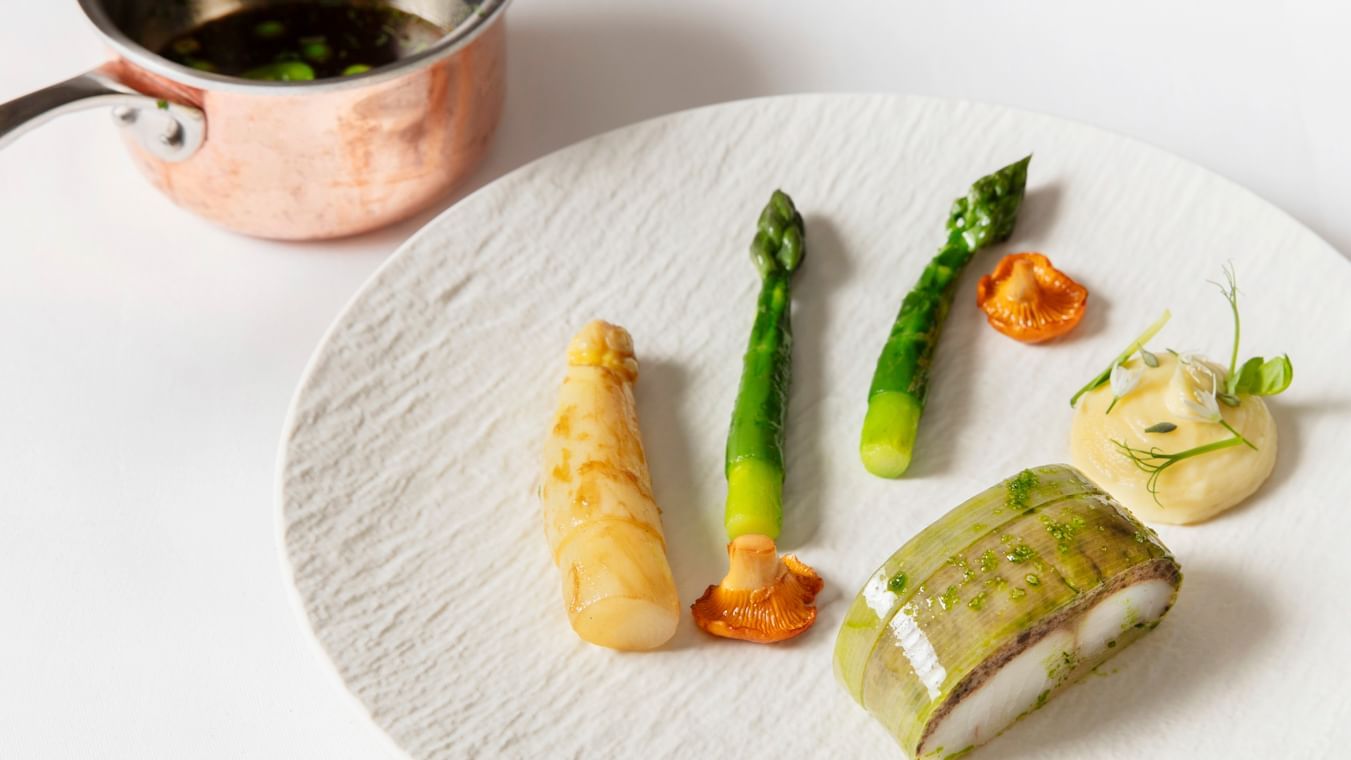 Dining dish featuring fresh asparagus, mushrooms, and a delicate fish fillet at Warwick Hotels and Resorts