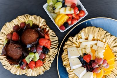 Gourmet muffins and cheese slices on golden plates, with a small bowl of fresh mixed berries at Rodd Charlottetown Hotel