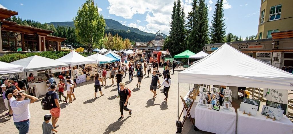 Outdoor market with vendor tents and visitors in Whistler Village