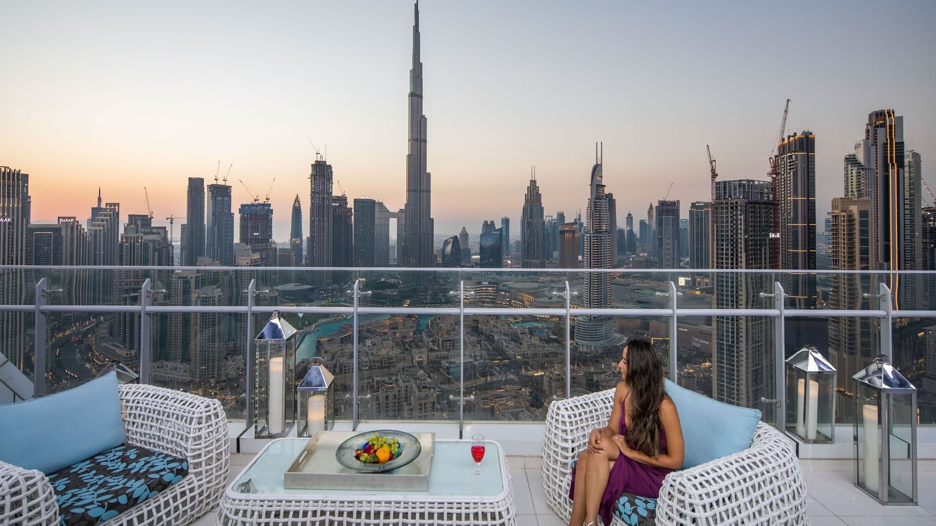 A lady on a wicker chair overlooking the Burj Khalifa from the balcony at DAMAC Maison Distinction