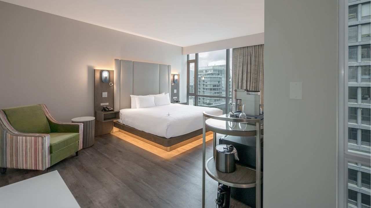 Hotel room with large bed, chair, and city view.