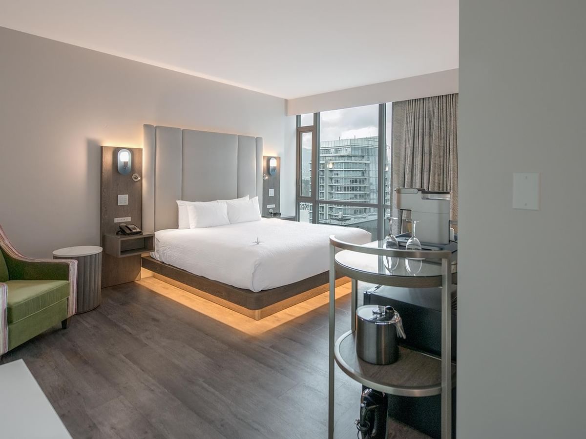 Hotel room with a king bed, large window, and city view.