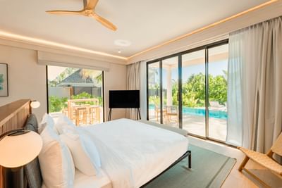 Bright 2-Bedroom Beach Villas at Ananea Madivaru Maldives with a bed, stylish decor, glass doors opening to a poolside deck