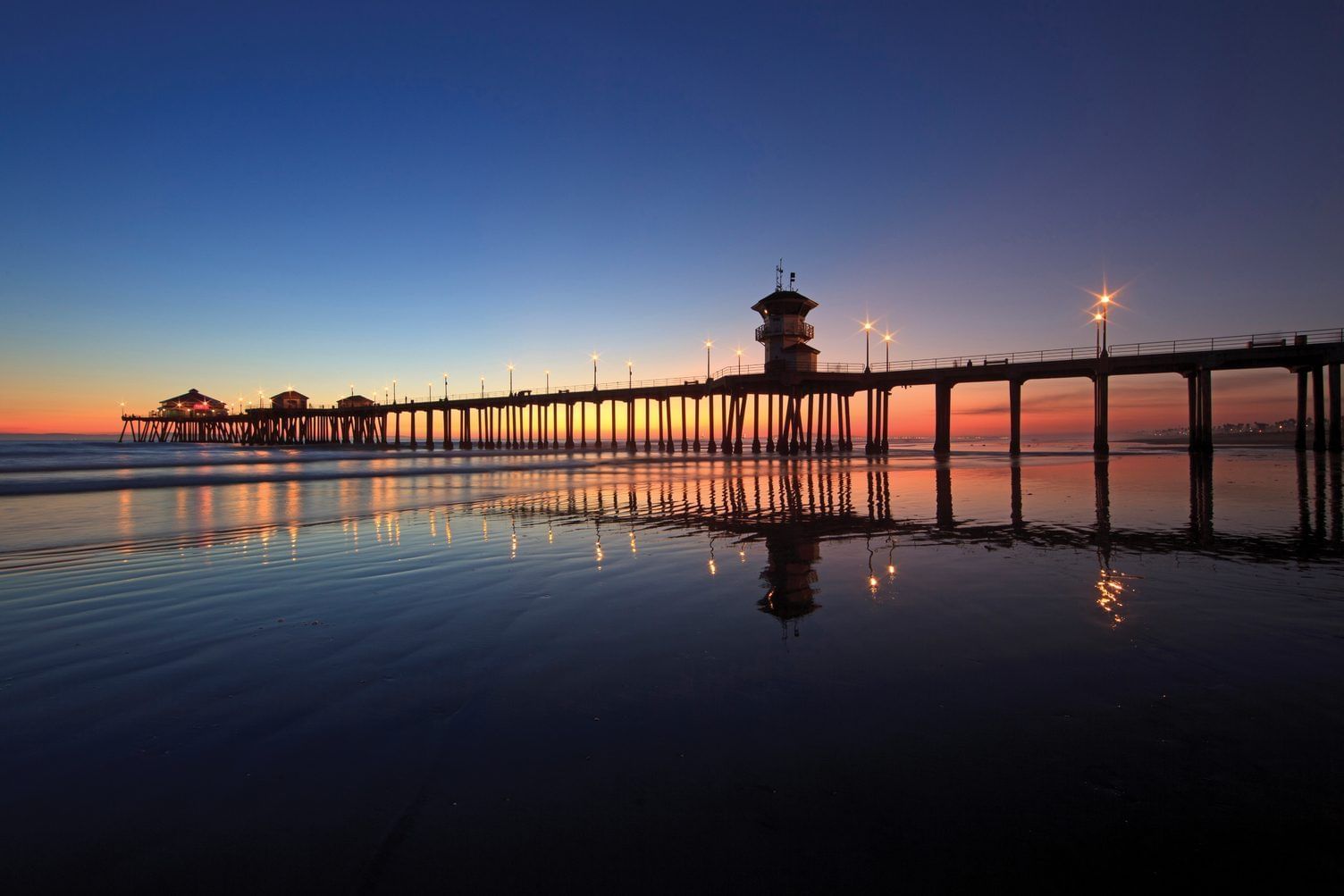 a long pier extends into the water at sunset
