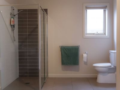 Green towels and white toilet next to glass shower in bathroom at La Trobe University Regional Housing – Melton.