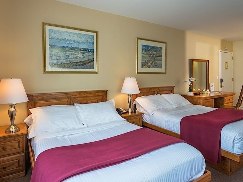 Two cozy beds with lamps and framed art in a warm Double Room at Chelsea Savoy Hotel New York.