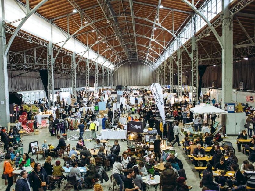 Besuchermesse mit Designständen in großer Halle.