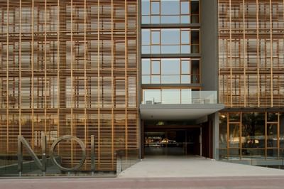 NOI Blend Colchagua facade with wood slats by a stone walkway under a clear sky