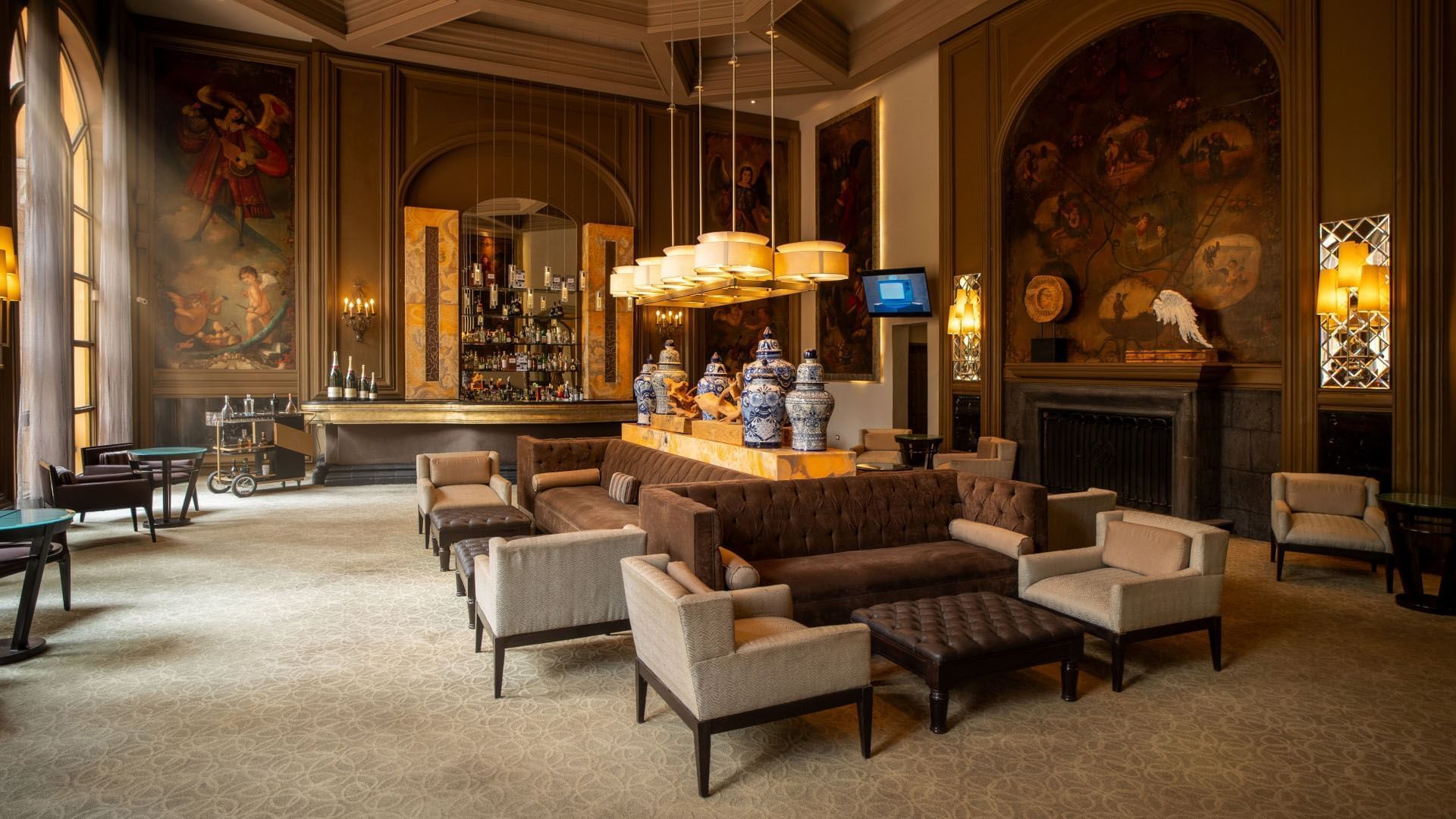 Luxurious Los Murales bar featuring plush brown sofas and historic wall art at Quinta Real Monterrey