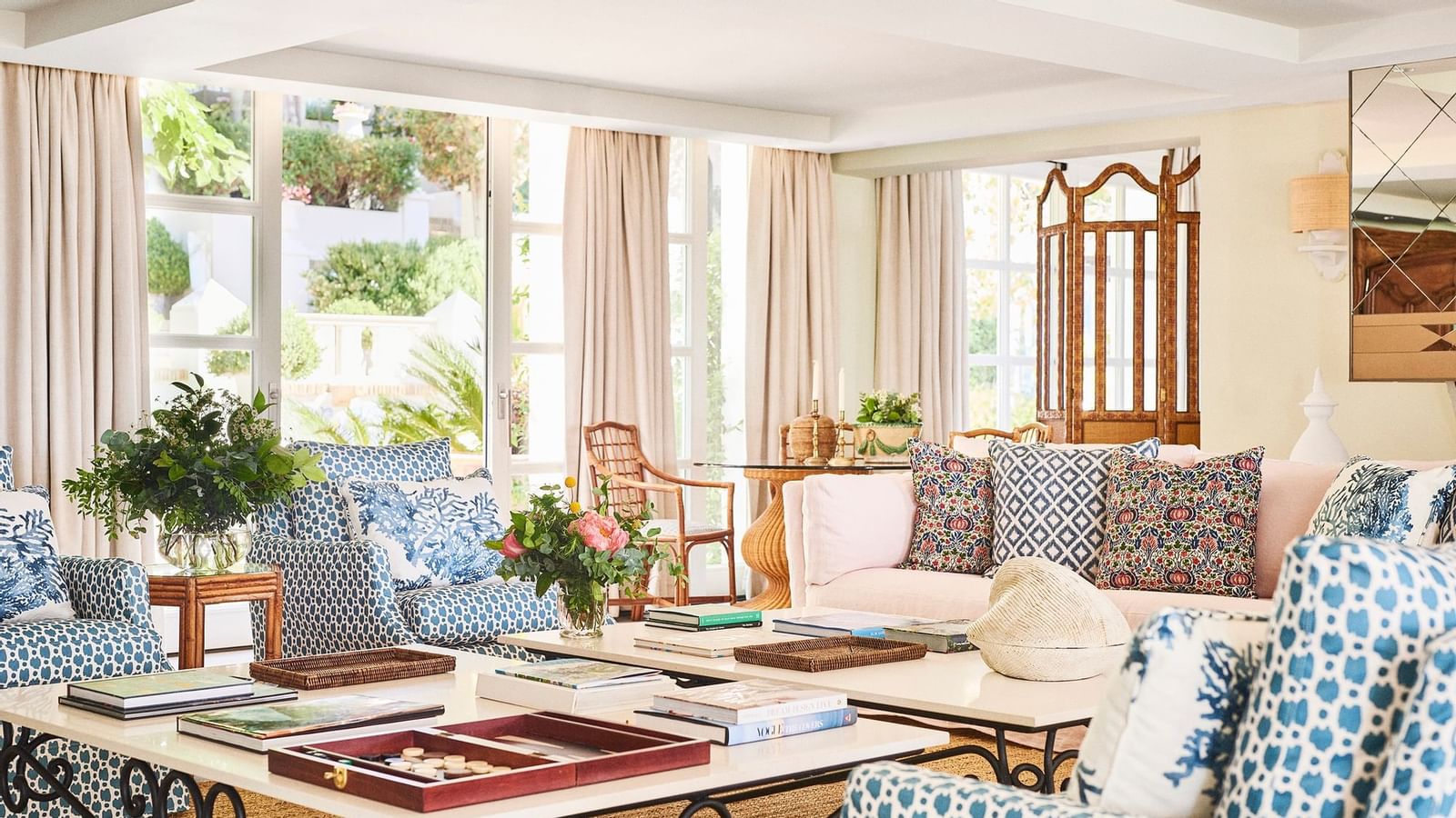 Lounge with patterned seating and tables placed in front of large glass doors leading to a garden at the Marbella Club