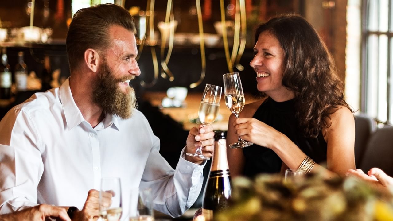 Two people toasting with champagne in a restaurant.