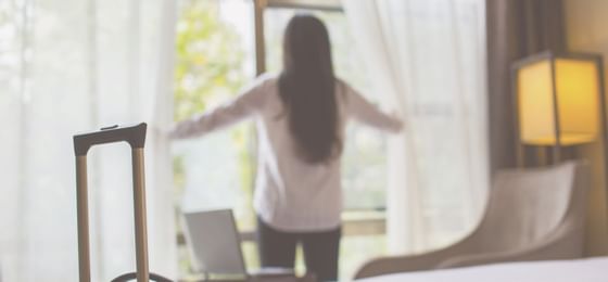 A woman spreading the window curtains at Barcelona Apartment