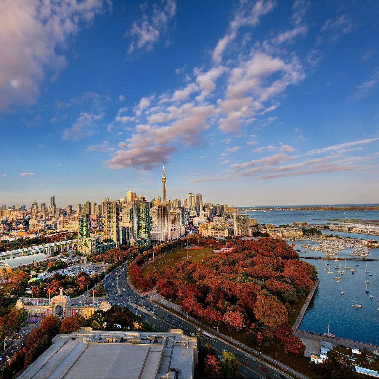 Aerial view of Toronto skyline with CN Tower and vibrant autumn trees surrounding waterfront marina at Hotel X Toronto