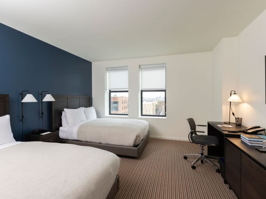 Two feather-topped beds with work desk in Double Room at The Study Hotel at Johns Hopkins