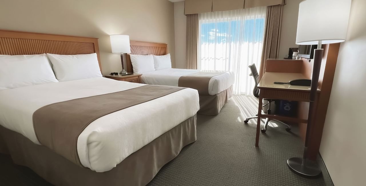 Hotel room with two beds, work desk, chair, and window