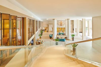 Staircase leading down to the lobby area with chandelier & comfy seating at Eastin Hotels