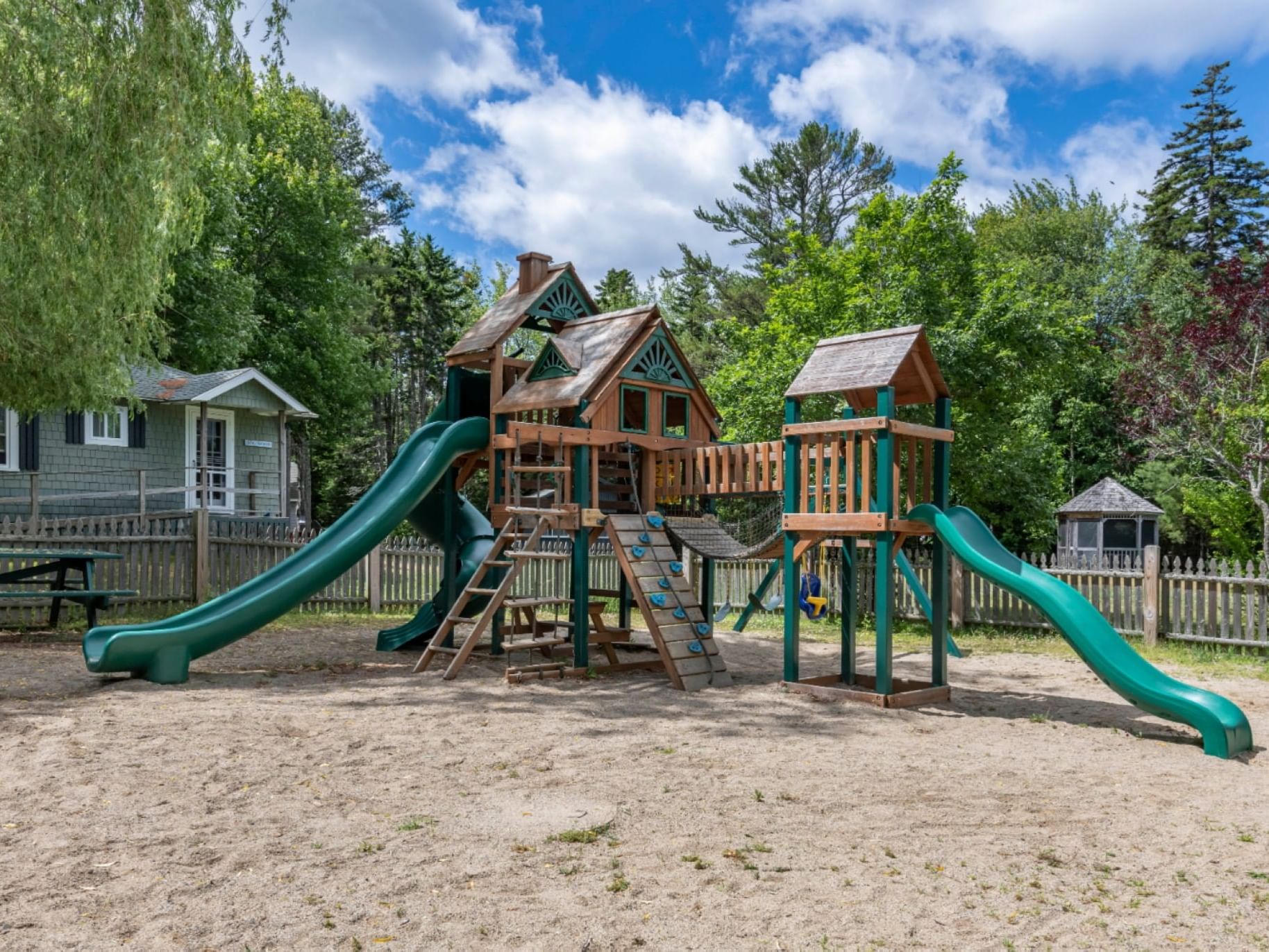 A sandy playground with swings and slides at The Bethel Inn Resort & Suites