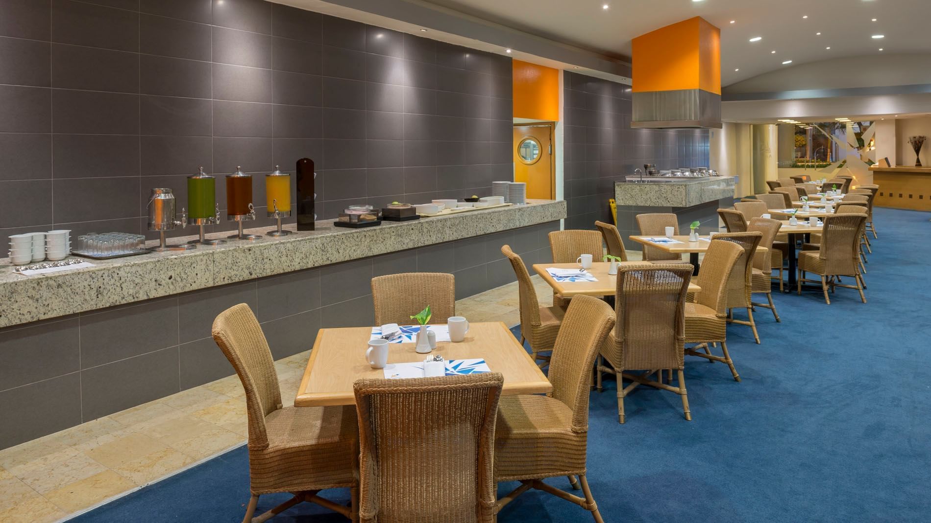 Dining area in Azulejos showing a long buffet counter, juice dispensers, and organized tables at Real Inn Nuevo Laredo