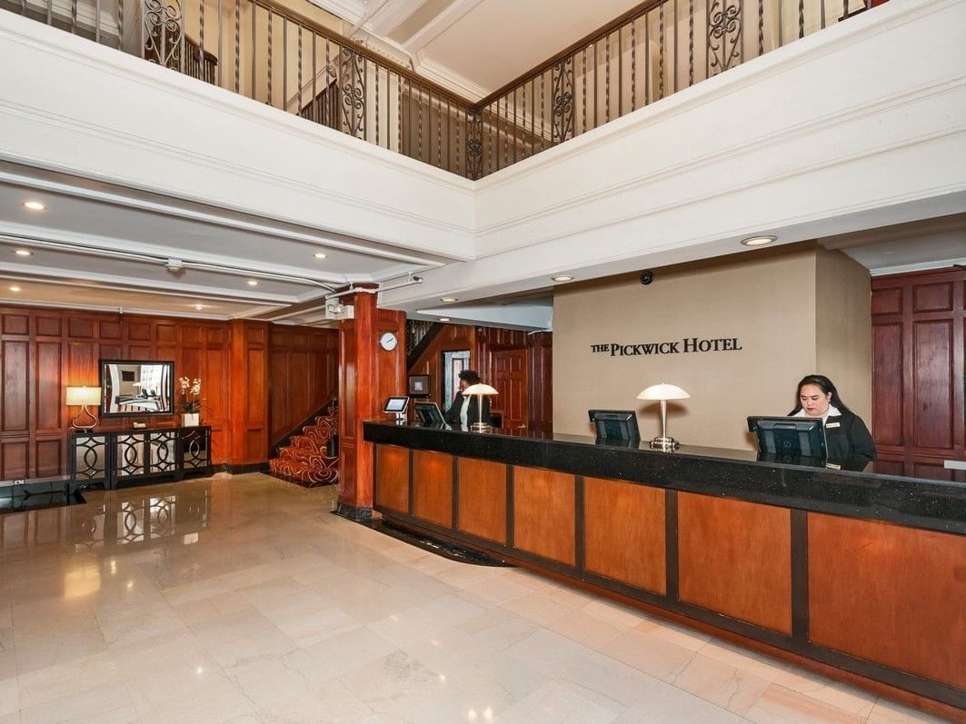 Reception area of The Pickwick Hotel with two receptionists behind the desk.