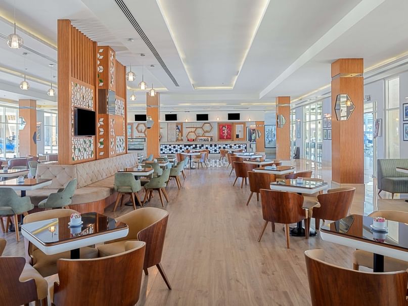 Modern restaurant with wooden floors, tables, and chairs, and decorative elements on the walls and ceiling.