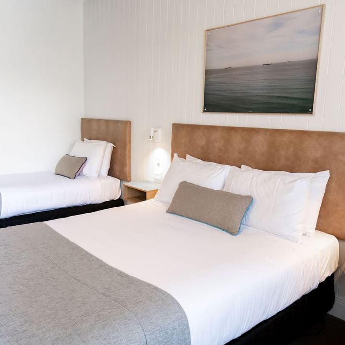 Two neatly made beds with pillows and blankets in a cozy hotel room at Mercure Charlestown.