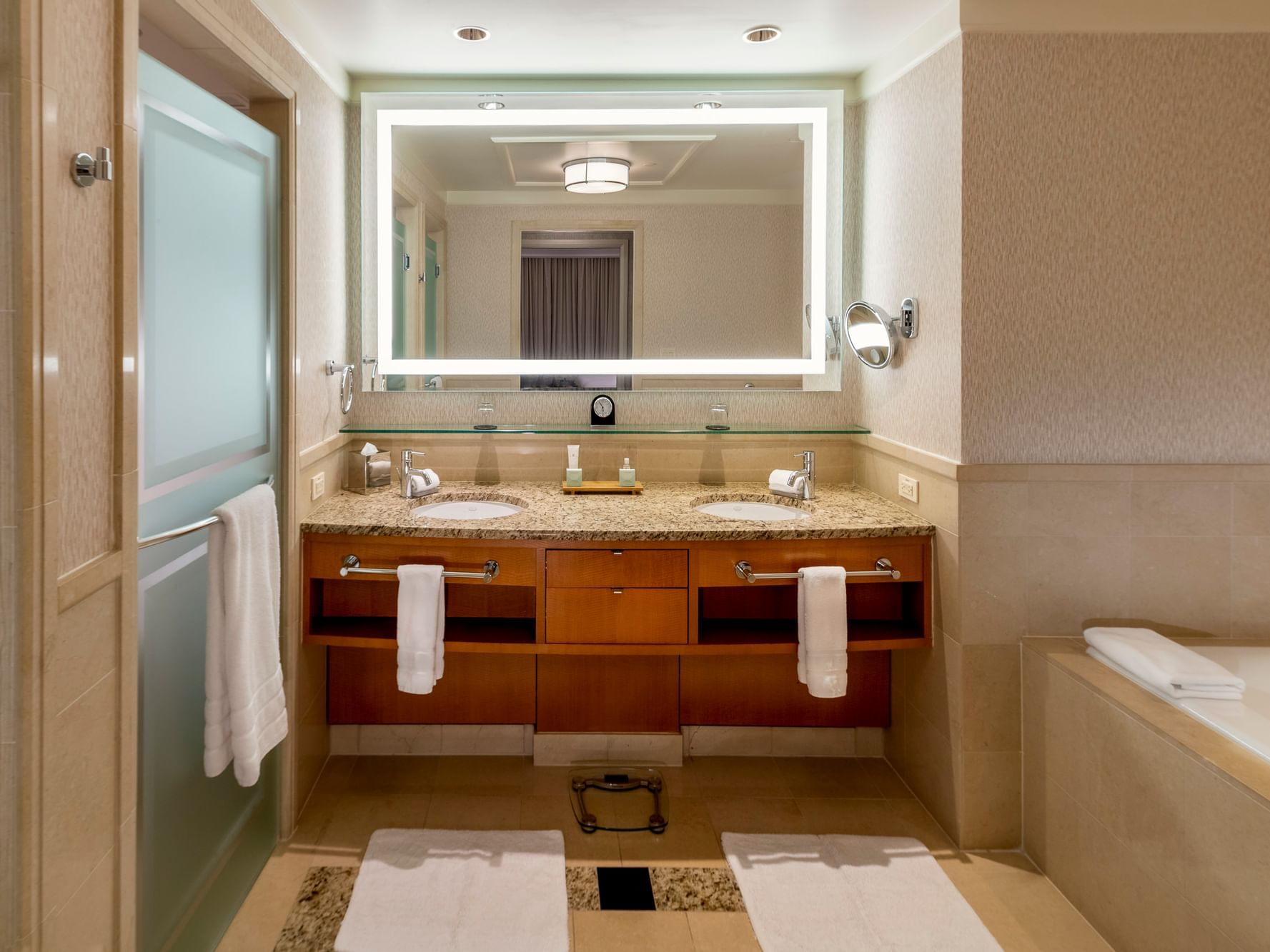 Luxury bathroom bathtub by the vanity with an illuminated mirror in Governor's Suite at The Umstead Hotel and Spa