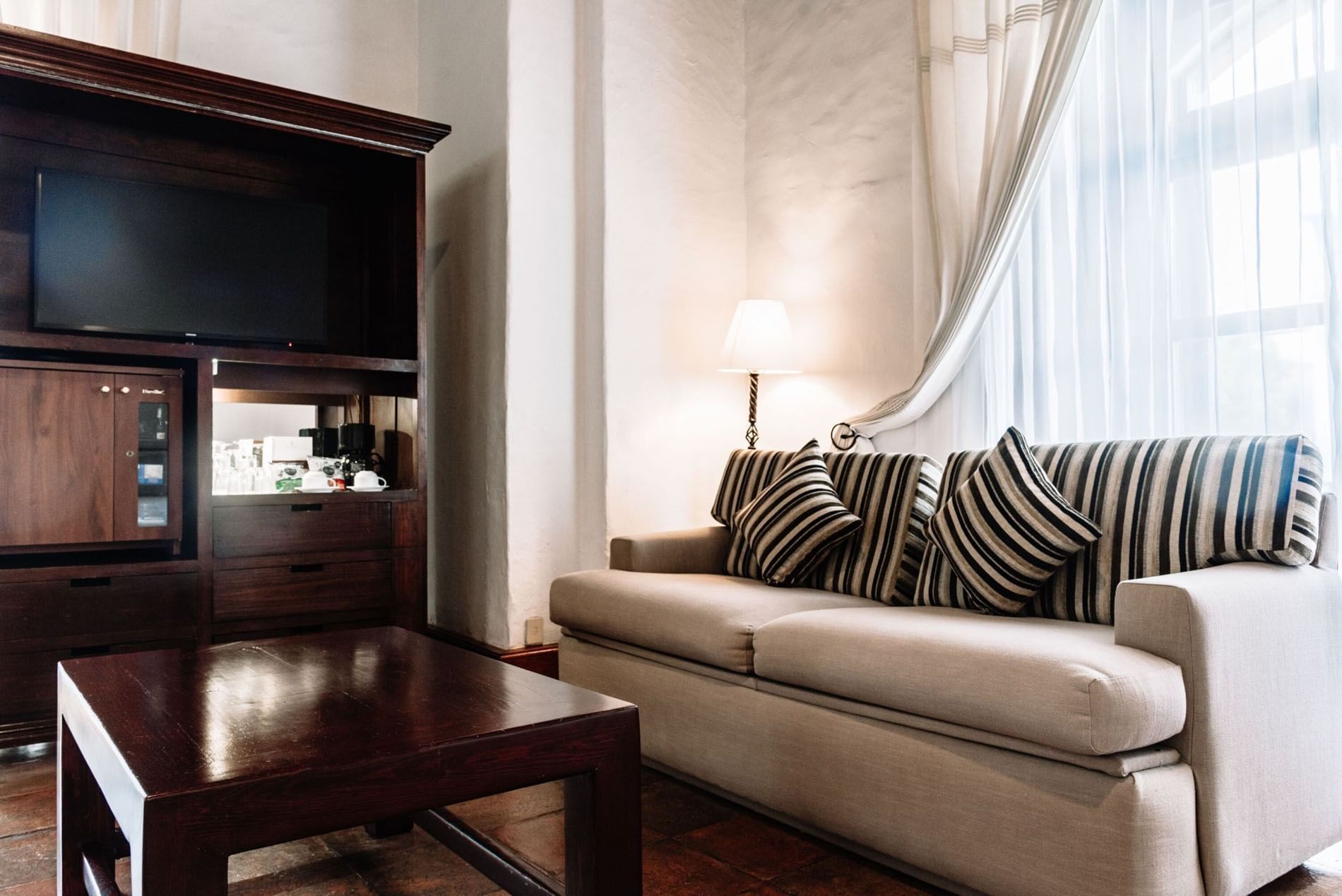 TV lounge area with plush seating and a wooden coffee table in the 2 Double Grand Class Suite at Quinta Real Oaxaca