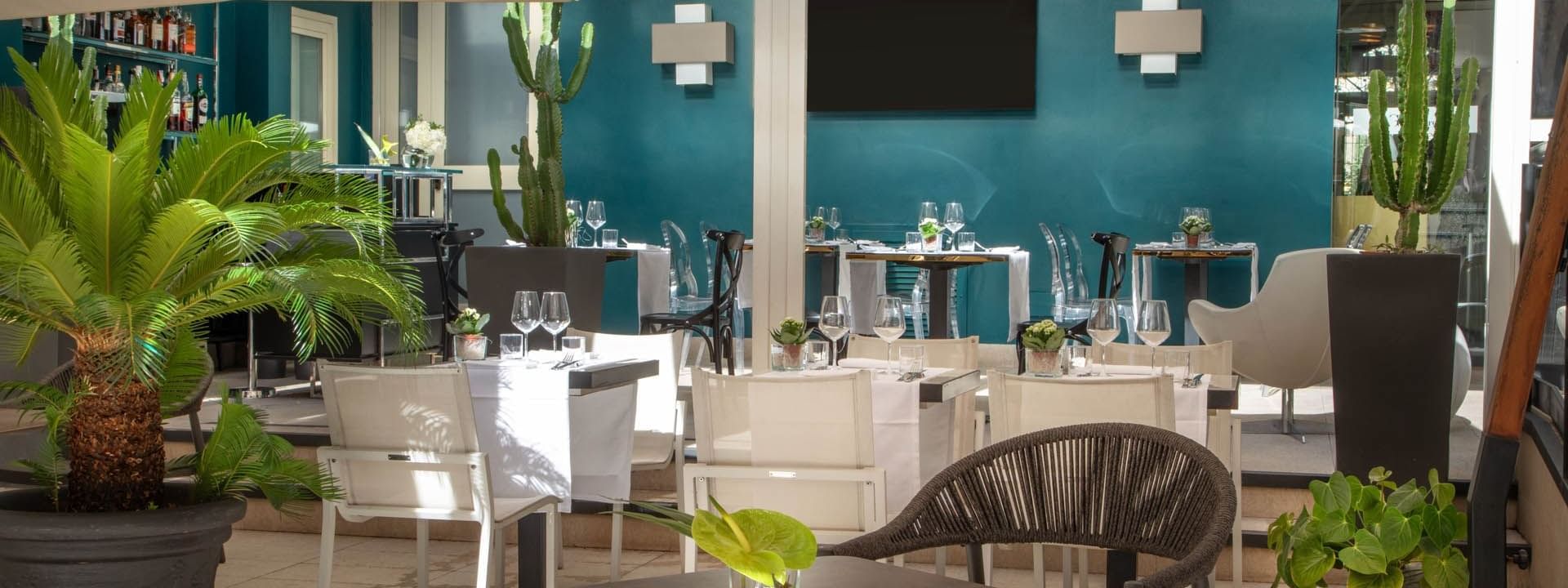 Elegant Guardian Dehors outdoor dining at The Guardian Hotel with modern furniture, lush plants, and a vibrant blue wall