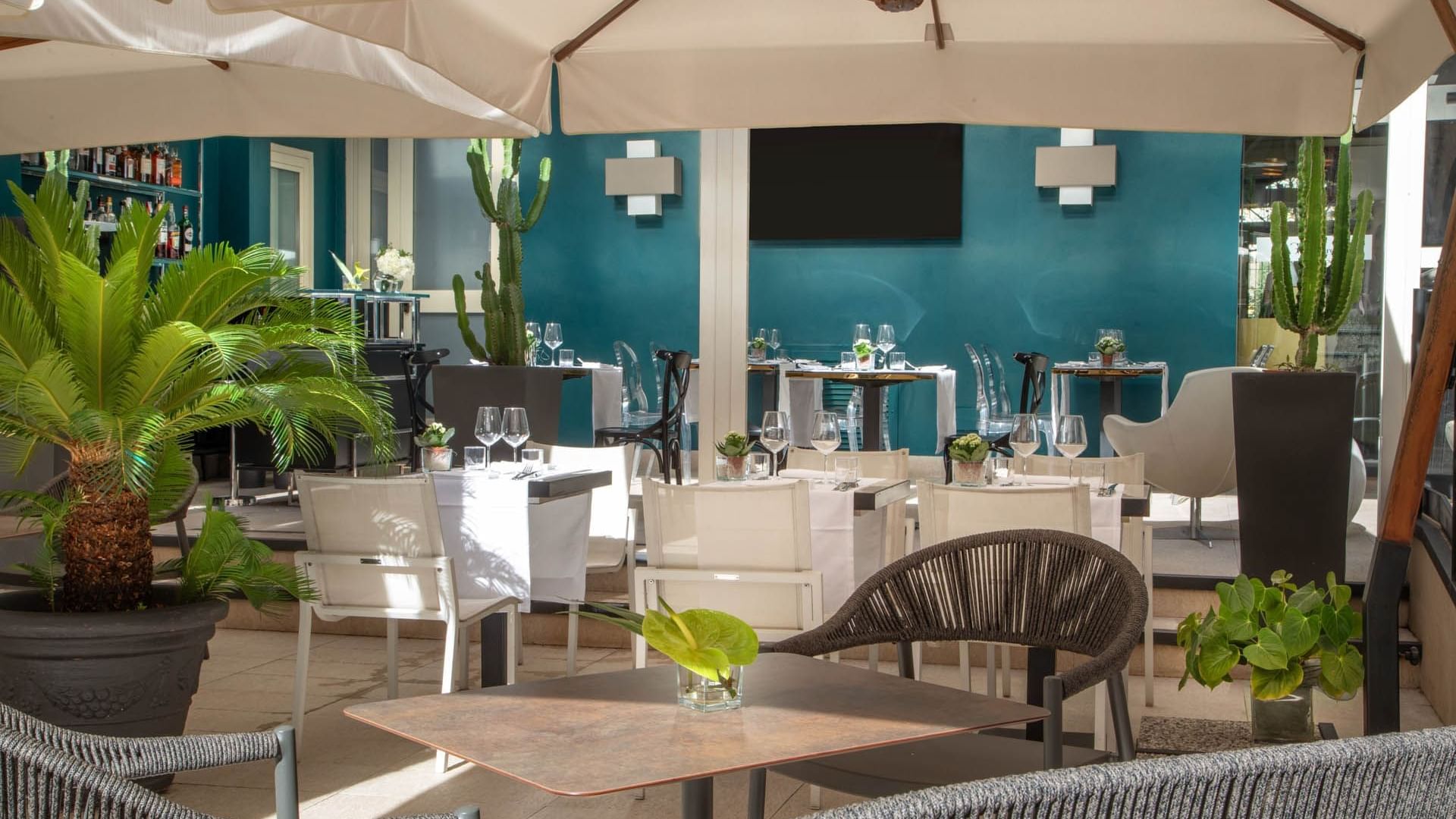 Elegant Guardian Dehors outdoor dining at The Guardian Hotel with modern furniture, lush plants, and a vibrant blue wall