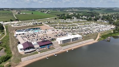 Aerial view of lakeside Off Shore Resort with a pool, parking lot, and RV campground surrounded by lush green hills