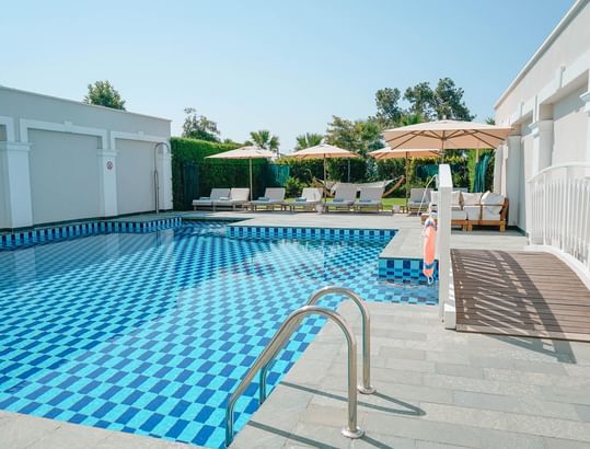Sun loungers with patio umbrellas by pool deck at Superior Villa in Titanic Deluxe Golf Belek