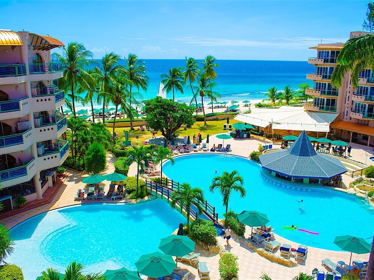 Outdoor pool area with sunbeds and patio umbrellas overlooking the sea at Accra Beach Hotel & Spa