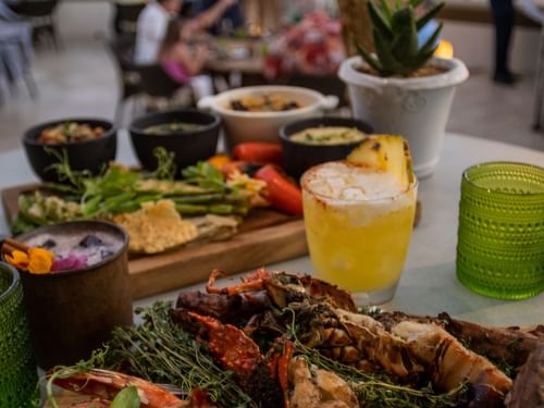 De Cortez Grill and Restaurant con un plato de langosta a la parrilla, espárragos y diversas salsas en Hacienda del Mar Los Cabos.