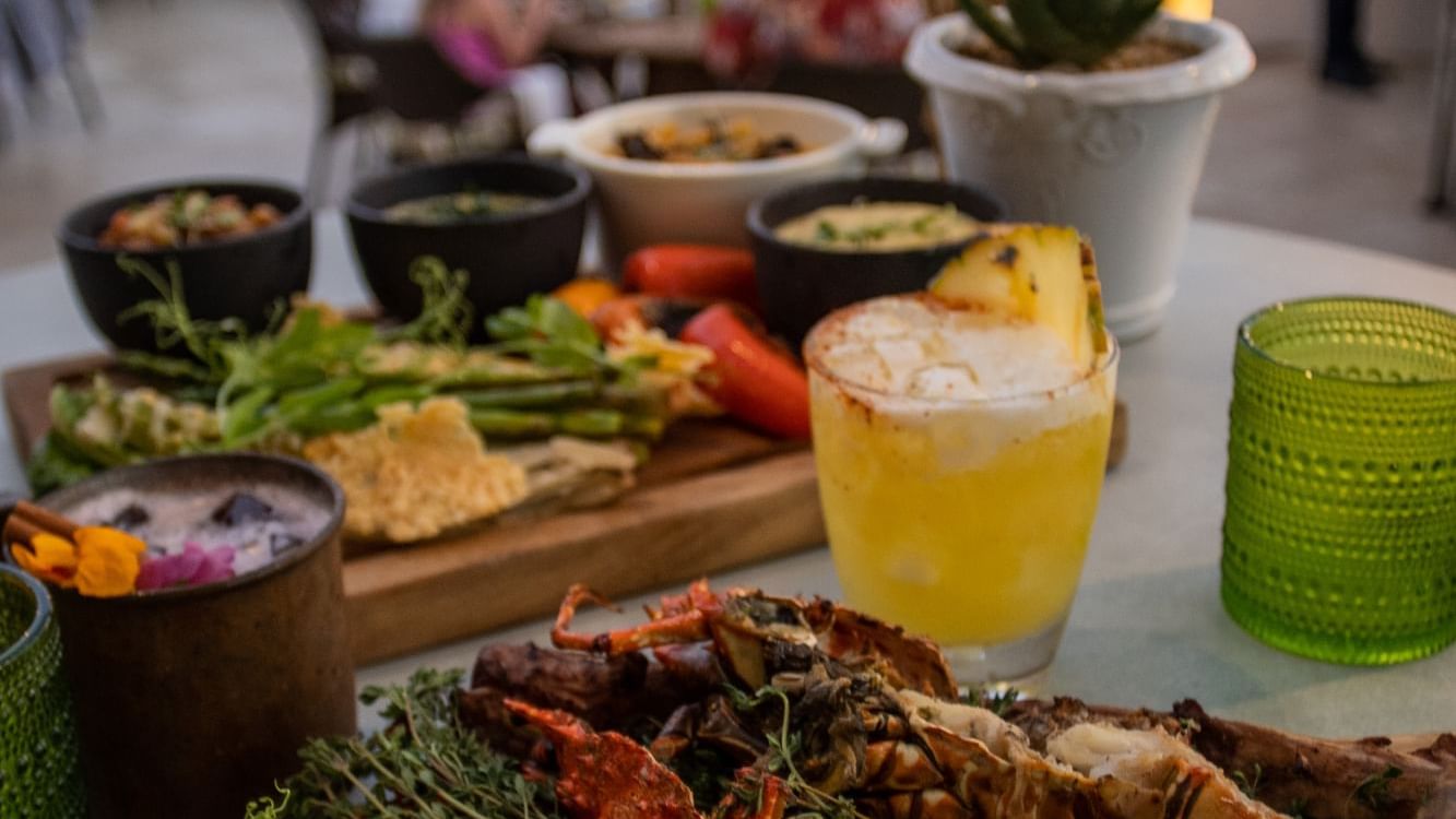 De Cortez Grill and Restaurant con un plato de langosta a la parrilla, espárragos y diversas salsas en Hacienda del Mar Los Cabos.