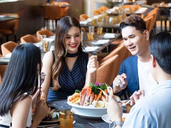 A group enjoying a meal together at a restaurant, sharing dishes and engaging in conversation.