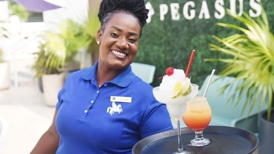 Server holding cocktails in Pool Bar & Lounge at Jamaica Pegasus Hotel, featuring the best restaurants in Kingston Jamaica 