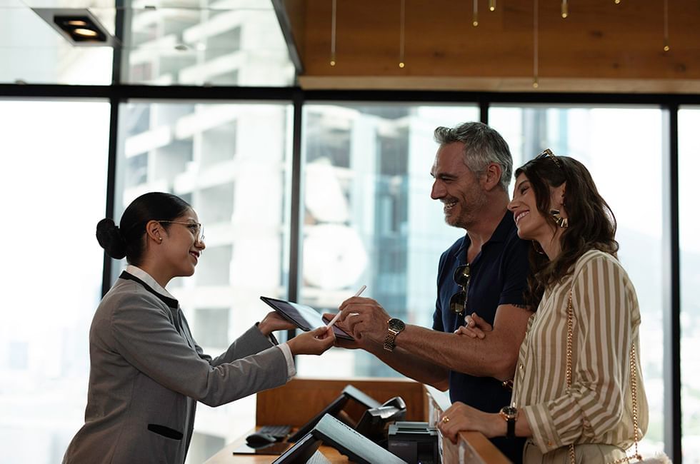 Receptionist assists a couple at a hotel check-in counter at Live Aqua Resorts and Residence Club