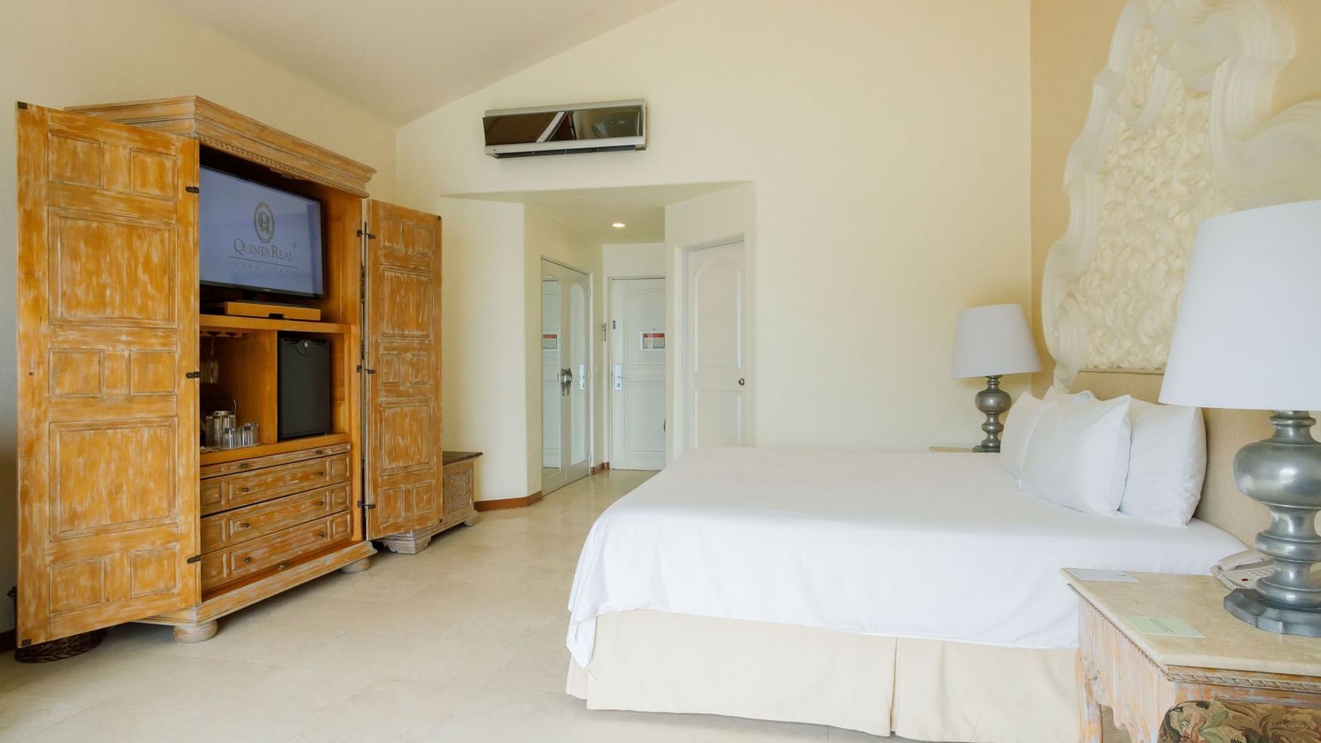 King Master Suite  featuring a king bed, ornate headboard, and a large wooden armoire at Quinta Real Acapulco