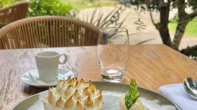 Dessert sur une table en bois avec une tasse de café et une vue sur le jardin.