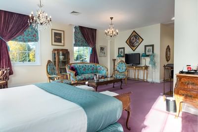 Interior view of a room with bed, Tv and comfy couch at Orsett Hall Hotel