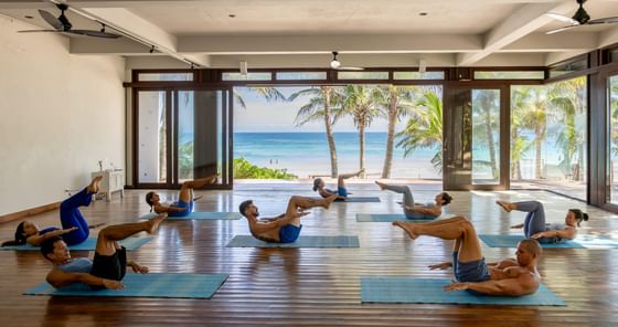 Bright, spacious fitness studio with people doing core exercises overlooking the ocean at the luxurious La Zebra Hotel