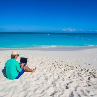 Man with a laptop at the beach near the Somerset On Grace Bay 