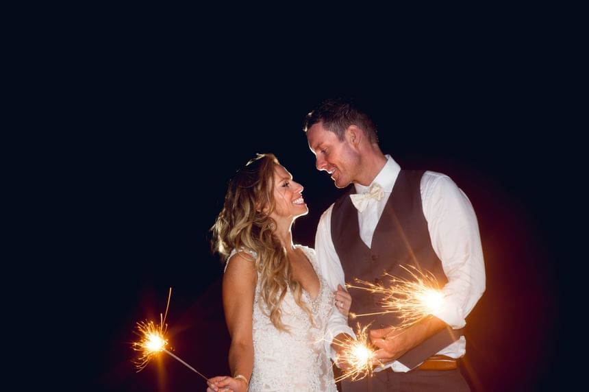 Wedding couple holding fireworks in Ocean Place at night