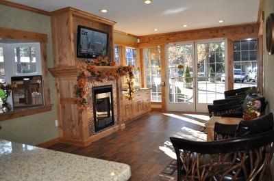 Cozy lobby with wood floors, a wood fireplace mantle, and seating next to glass French doors at Americana Village Suites
