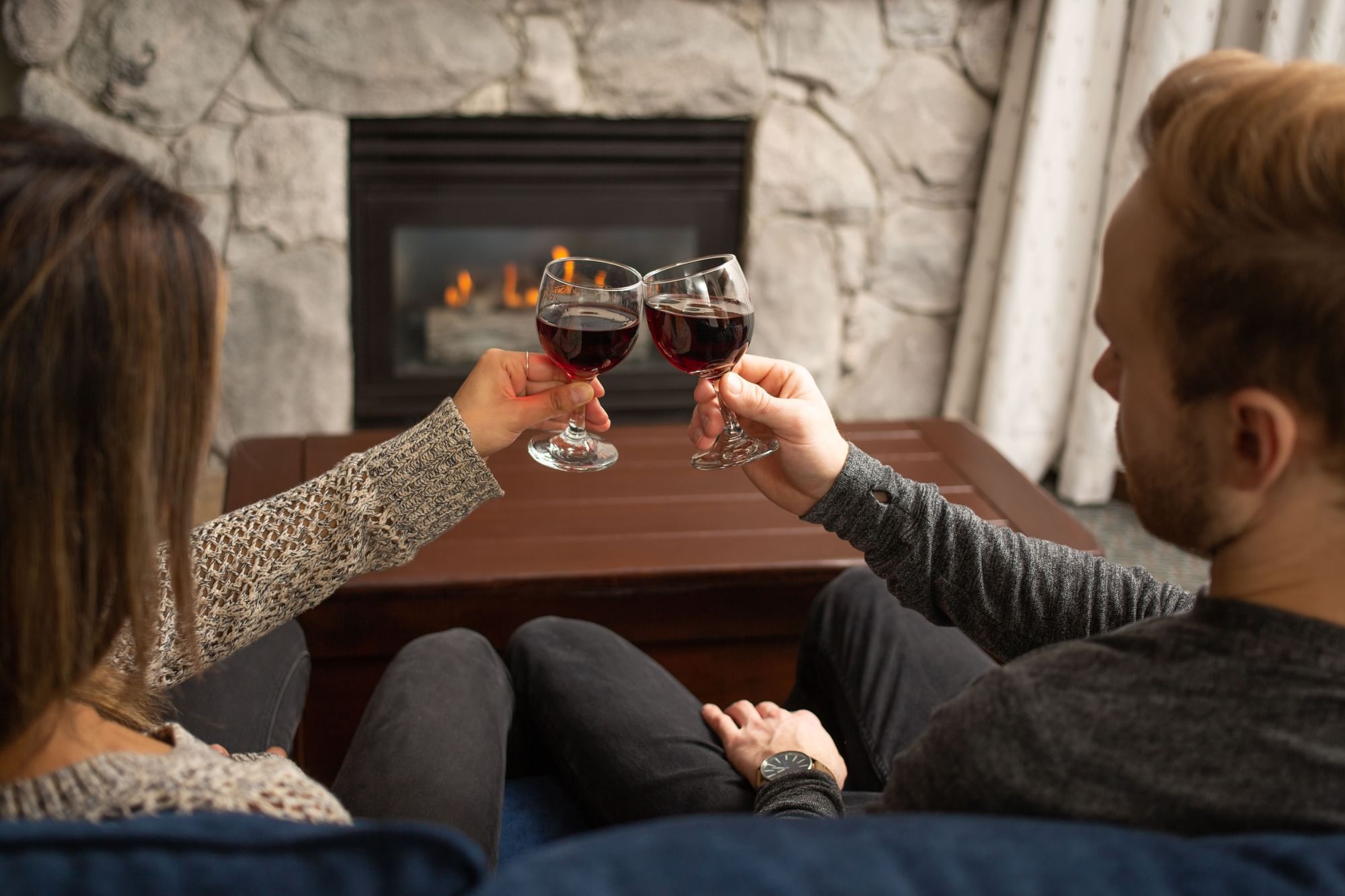 Couple toasting wine in a living area with firepit at Blackcomb Springs Suites